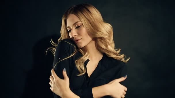 Blonde woman with curly hair posing on black background in studio — Stock Video