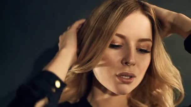 Mujer rubia con pelo rizado dorado posando sobre fondo negro en estudio — Vídeos de Stock