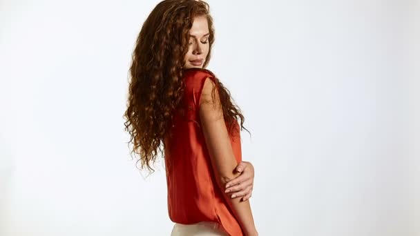 Bruna donna con i capelli ricci in posa su sfondo bianco in studio — Video Stock