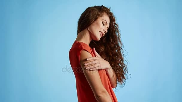 Mujer morena con el pelo rizado posando sobre fondo azul en estudio — Vídeos de Stock