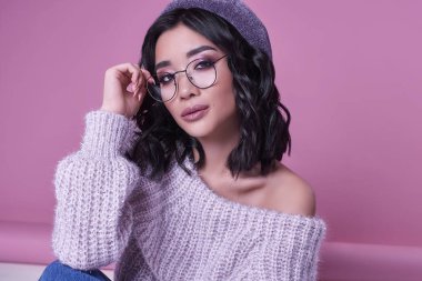 Parlak pembe bir arka plan üzerinde mor süveterli güzel şirin Asyalı kız