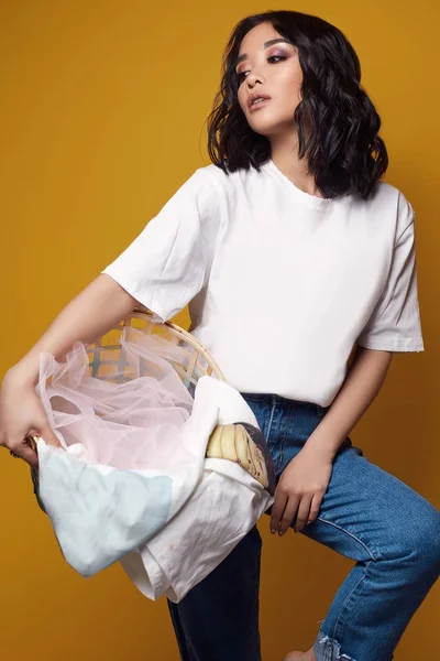 Елегантна сексуальна азіатська дівчина в джинсах і біла футболка на яскравому фоні — стокове фото