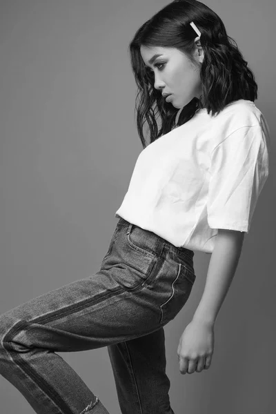 Elegante sexy Aziatische meisje in jeans en witte t-shirt op heldere bac — Stockfoto