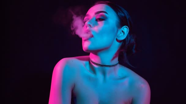魅力的肖像诱人的华丽的黑发妇女吸烟电子香烟在霓虹灯在演播室 — 图库视频影像