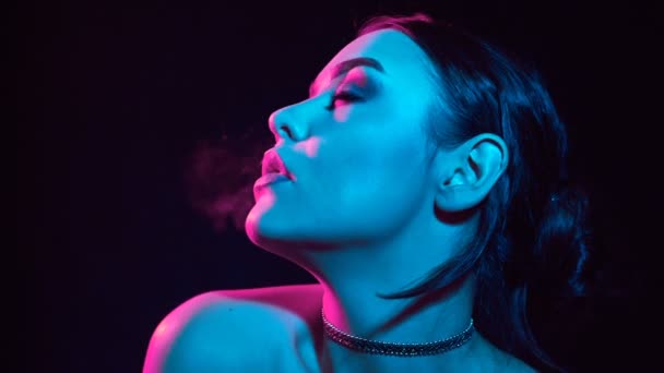 魅力的肖像诱人的华丽的黑发妇女吸烟电子香烟在霓虹灯在演播室 — 图库视频影像