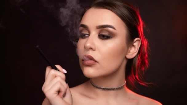 スタジオで電子タバコを吸ってする魅力魅惑的なゴージャスなブルネットの女性の肖像画 — ストック動画