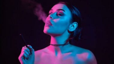 Ağır çekim portre glamour baştan çıkarıcı muhteşem bir esmer kadın sigara elektronik sigara neon renkli stüdyo ışık