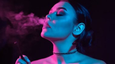 Ağır çekim portre glamour baştan çıkarıcı muhteşem bir esmer kadın sigara elektronik sigara neon renkli stüdyo ışık