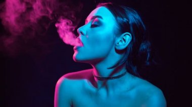 Ağır çekim portre glamour baştan çıkarıcı muhteşem bir esmer kadın sigara elektronik sigara neon renkli stüdyo ışık