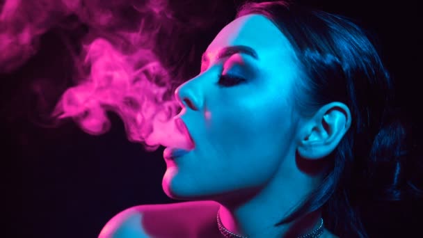 慢动作肖像魅力诱人的华丽黑发妇女吸烟电子香烟在霓虹灯在演播室 — 图库视频影像