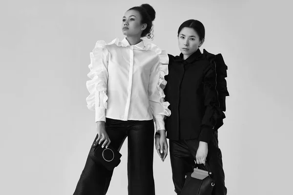 Elegantní pár černých a asijských žen v módní černé a — Stock fotografie