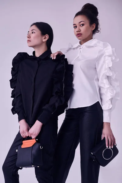 Elegáns pár divatos fekete-fehér öltöny fekete és ázsiai nők — Stock Fotó