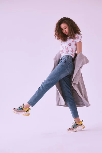 Eleganta svarta hipster kvinna med lockigt hår i pälsen och jeans — Stockfoto