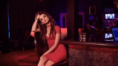 Muhteşem güzellik viski lüks iç cam ile barda oturan Kırmızı elbiseli genç esmer kadın portresi