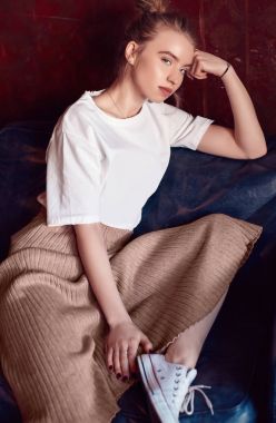 Beyaz tişört ve kanepede oturan elbise güzel hipster sarışın kadın