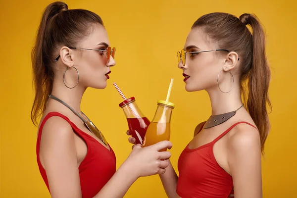 Dwie eleganckie hipsterskie bliźniaczki w czerwonej bluzce z drinkiem koktajlowym — Zdjęcie stockowe