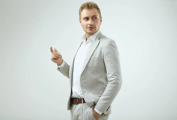 Handsome blonde man model in a fashion gray suit in studio — Stock Photo, Image