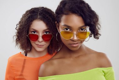 Yaz kıyafetleri ve parlak güneş gözlüğü takmış iki güzel hippi kız.