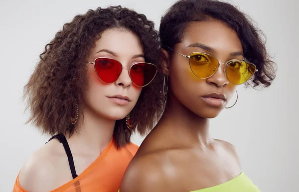Két gyönyörű fiatal hipster lány nyári ruhában és fényes napszemüvegben. — Stock Fotó