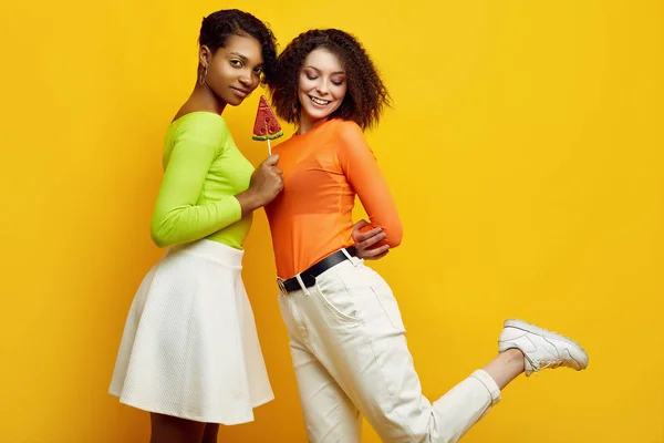 Två unga vackra hipster flickor i färgglada sommarkläder med klubbor — Stockfoto
