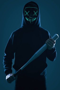 Siyah kapüşonlu ve neon maskeli beysbol sopalı isimsiz bir suçlu.