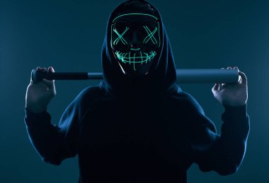Siyah kapüşonlu ve neon maskeli beysbol sopalı isimsiz bir suçlu.