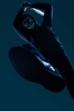 Siyah kapüşonlu ve neon maskeli beysbol sopalı isimsiz bir suçlu.