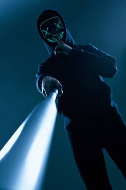 Siyah kapüşonlu ve neon maskeli beysbol sopalı isimsiz bir suçlu.