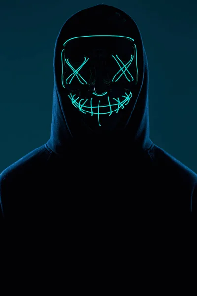 Анонімний чоловік в чорному светрі ховає обличчя за неоновою маскою — стокове фото