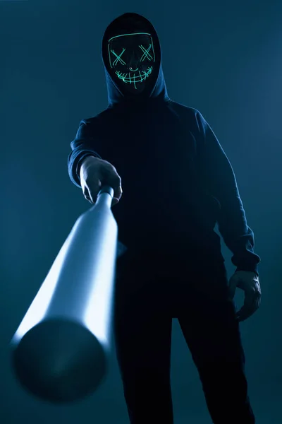 Anonimowy przestępca z kijem baseballowym w czarnej bluzie i neonowej masce — Zdjęcie stockowe
