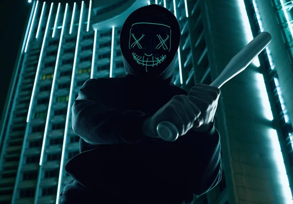 Анонимный преступник с бейсбольной битой в черной толстовке и неоновой маске — стоковое фото