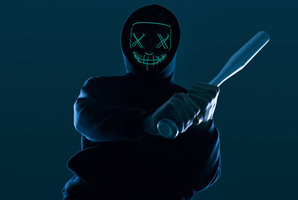Anonymous criminal man with baseball bat in a black hoodie and n