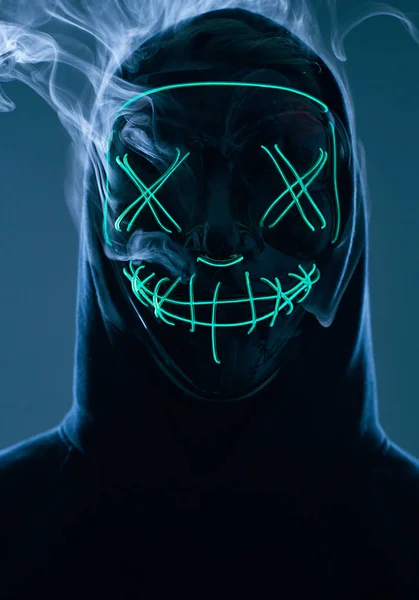 Hombre anónimo escondiendo su cara detrás de la máscara de neón en un humo de color —  Fotos de Stock