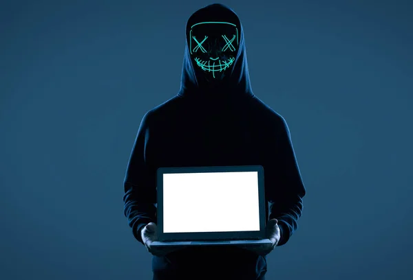 Hombre anónimo con capucha negra y máscara de neón hackeando un ordenador —  Fotos de Stock
