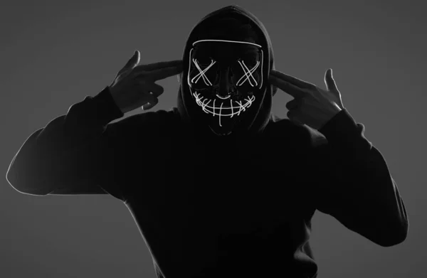 Anonieme man in zwarte hoodie verbergt zijn gezicht achter een neon masker — Stockfoto