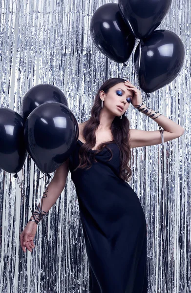 Elegant hispanic brunette woman in luxurious black dress holds balloons — 스톡 사진