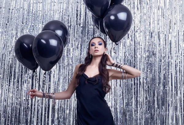 Elegant hispanic brunette woman in luxurious black dress holds balloons — 스톡 사진