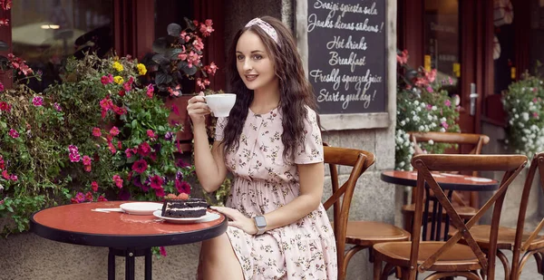 Молода вродлива дівчина на літньому одязі сидить за столом у кафе. — стокове фото