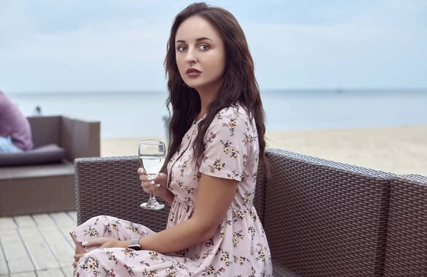Jong mooi helder meisje in een zomer jurk zitten op het strand — Stockfoto