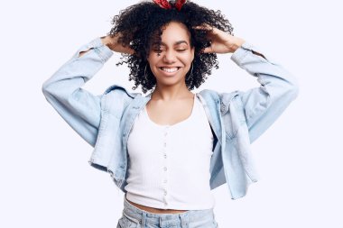 Beyaz stüdyo arka planında izole edilmiş kıvırcık saçlı, zarif siyah hippi kız modelinin şehvetli portresi.