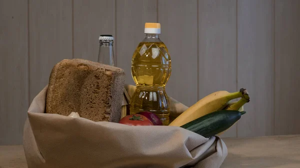 Ekmek, ayçiçeği yağı, domates, muz, salatalık, elma, elma, elma ve peynir dolu mutfak masasında..