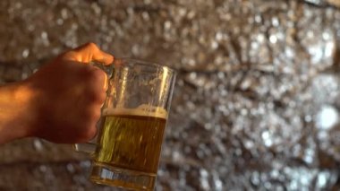 Bir adam elinde bir kupa bira tutuyor ve arkadaşı koluna büyük bir salatalıkla vuruyor. Arkadaşlar şakalaşıyor..