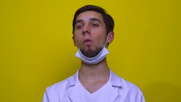 白いコートに医者と医療マスクが食べる 黄色の背景にコロナウイルスの概念 — ストック動画