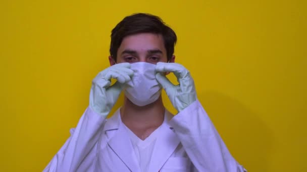 一位身穿白衣的医生摘下了他脸上的医疗面具 黄原背景下的考拉威斯概念 — 图库视频影像