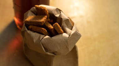 Bir bardak bira ve masada kraker olan bir kese kağıdı..