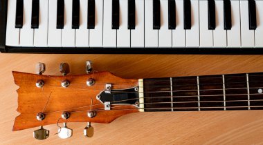 Ahşap bir arka planda akustik gitar ve piyano tuşları. Müzik konsepti.