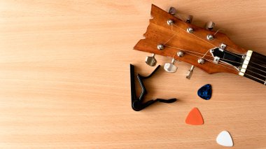 Akustik gitar, capo ve penalar tahta bir arka planda yatar. Kopya alanı ile Coronavirus salgını müzik kavramı.