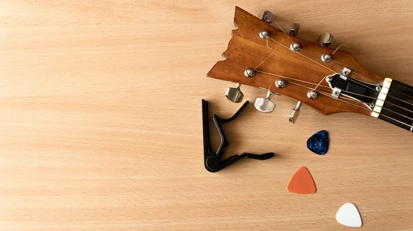 Akustik gitar, capo ve penalar tahta bir arka planda yatar. Kopya alanı ile Coronavirus salgını müzik kavramı.