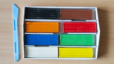 Ahşap bir masanın üzerinde çok renkli çocuk plastikçesi parçaları..