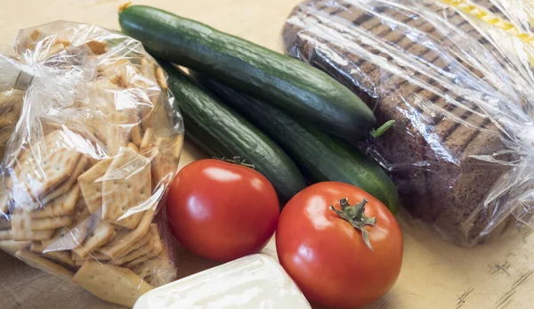 Koronavirüs sırasındaki muhtaç ve açlara yiyecek bağışı. Kraker, ekmek, salatalık, muz, domates, peynir eski ahşap masada..